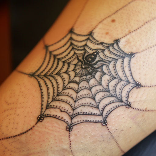 Spider web tattoo with lace-like design on white background