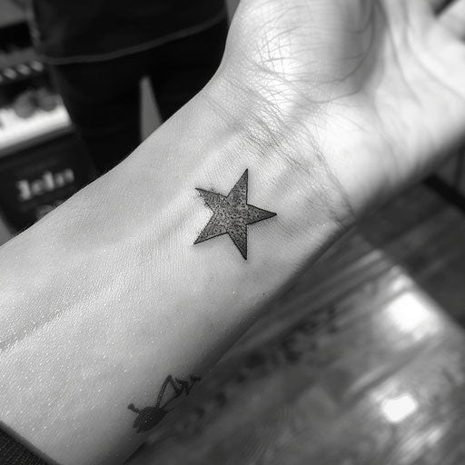 Small wrist tattoos of a star, in the style of Steve McNiven
