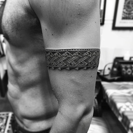 Tribal pattern armband tattoo, in the style of Guy Aitchison, on upper arm