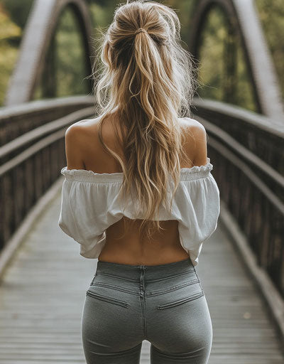 Blonde woman with bun hairstyle on bridge, high-waisted jeans
