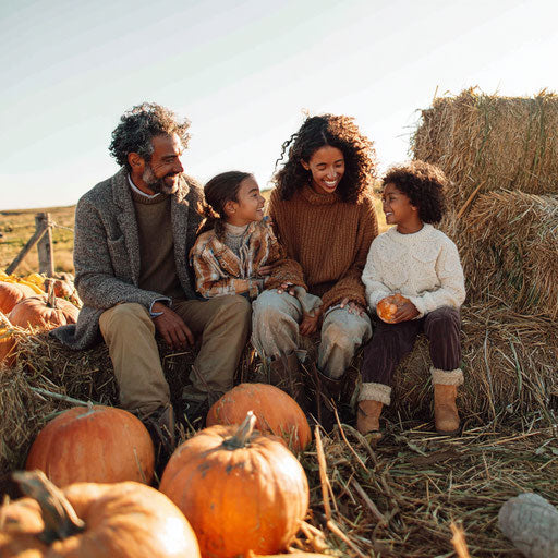 A family joyfully plays with pumpkins and hay outdoors