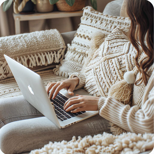Working on laptop on cozy sofa surrounded by pillows