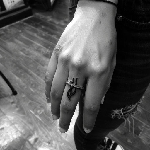 Wedding ring tattoo with small flame design on finger
