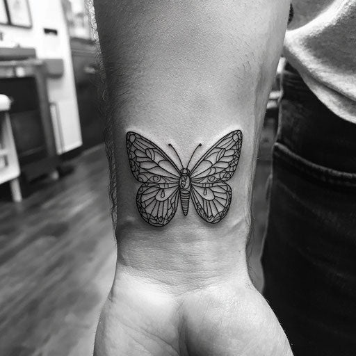 Butterfly tattoo men on the wrist with tribal lines