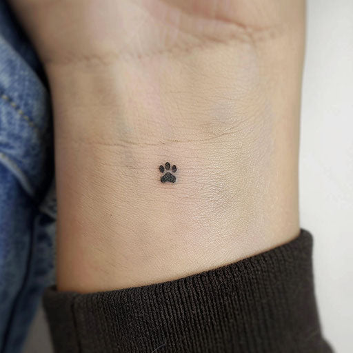 Small black paw print tattoo on white background