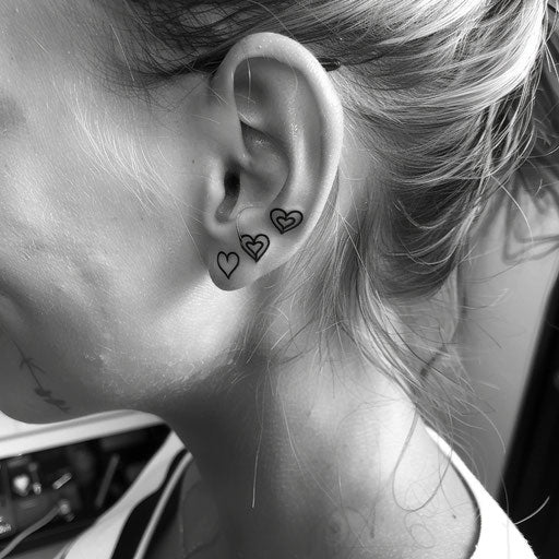 Ear tattoos in the style of Ami James featuring minimalist hearts