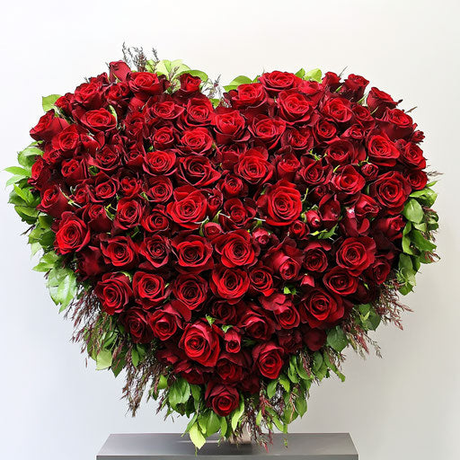 Heart-shaped arrangement of red roses on white background